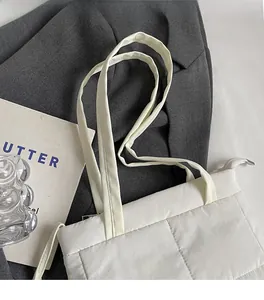 Detail of white quilted tote bag featuring reinforced stitching and a wide comfortable strap