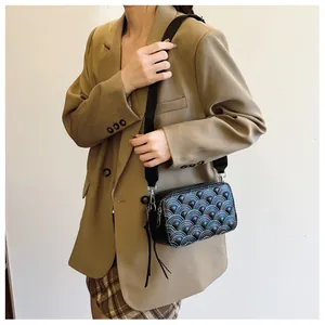Detail of black PU crossbody bag featuring colorful semi-circle embroidery and wide strap