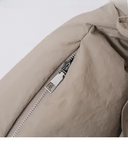 Close-up of sleek silver rectangular zipper puller on pleated nylon commuter bag