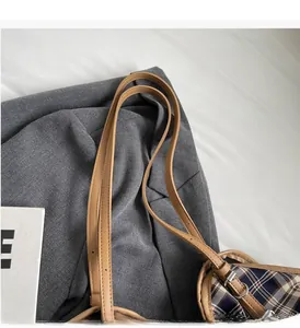 Close-up of durable leather handles and classic plaid pattern on a large tote bag
