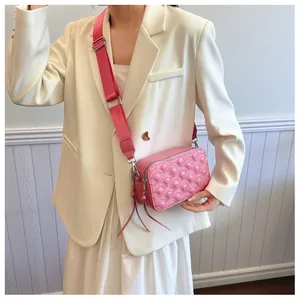 Detail of pink quilted crossbody bag with stylish wide shoulder strap on model