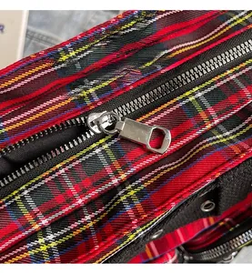Detailed macro view of the smooth metal zipper on a red and black plaid tote bag