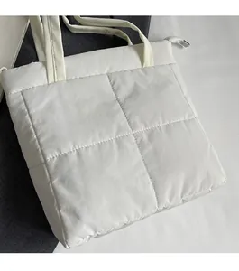Top view of a white quilted tote bag featuring a padded square pattern and zipper closure