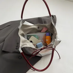 Silver PU tote bag with red bow straps showing large capacity interior with daily items