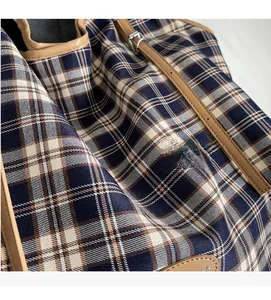 Detail showing soft checkered canvas fabric texture and premium leather strap of the tote