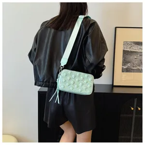 Detail view of light green quilted crossbody bag with wave texture and tassel zipper