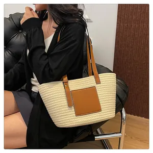Close-up of woven straw tote bag featuring brown leather handles and textured stitching