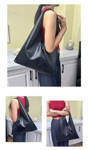 Close-up of minimalist black oversized tote with vintage crinkle texture and silver rivets
