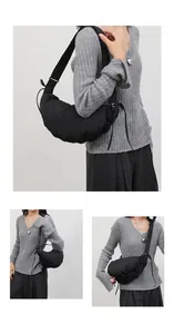 Detail of a black crescent crossbody bag with quilted texture and adjustable shoulder strap