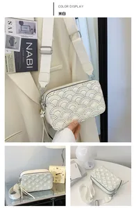 Detail of off-white rectangle crossbody bag with rainbow quilting and wide woven strap