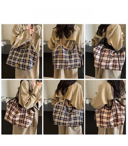 Detail view of large canvas plaid tote bag with brown leather straps and buckle decor