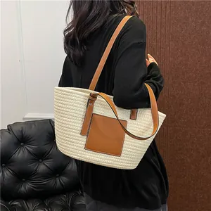 Minimalist straw woven tote bag with brown leather handles and decorative patch for travel