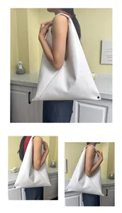 Detail of the white triangle origami tote with soft pleated texture and vibrant red lining