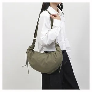 Detail view of army green crescent bag with pleated fabric and side drawstring detail