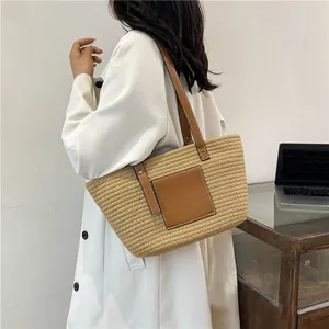 Straw tote bag with brown leather straps and pocket shown on a model for casual style