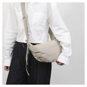 Detail of beige pleated crescent bag with adjustable wide shoulder strap for women