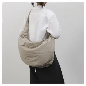 Detailweergave van de hobo-tas stof met natuurlijke geplooide textuur en brede riem