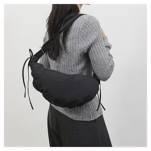 Macro detail of black pleated crescent bag with side drawstrings and nylon texture