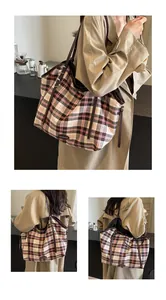 Close-up of a large checkered canvas tote bag with slim brown handles for school and work