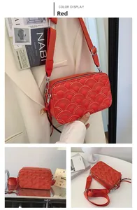 Detail of red crossbody bag with golden scale embroidery and wide canvas shoulder strap
