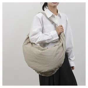 Detailaanzicht van de beige geplooide halve maan hobo tas met brede schouderriem