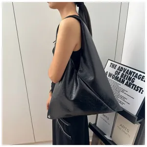 Detail of minimalist black hobo bag with unique triangular shape and wide shoulder strap