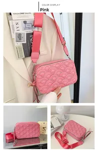 Pink camera bag with wave quilting and wide woven strap detail in outdoor setting