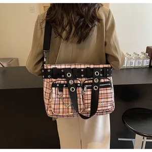 Detail of checkered tote bag featuring metal eyelets, silver chains, and front pockets