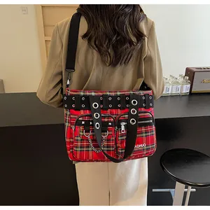 Detail showing red plaid tote bag with metallic rings and punk style chain accessories