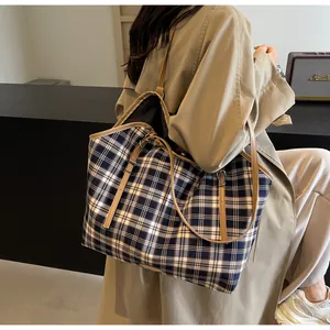 Detail shot of a large canvas plaid tote bag with khaki leather straps on a model back