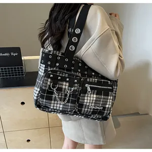 Close-up of black and white plaid tote bag with metal rivets and industrial utility chains