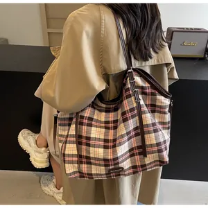 Detail of classic plaid tote bag with adjustable brown leather strap and canvas texture
