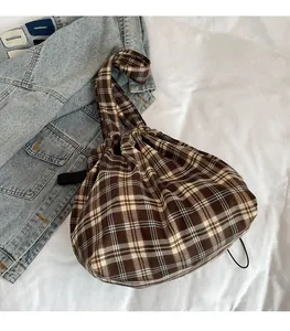 Close-up of vintage plaid bucket bag with drawstring closure on white textured fabric