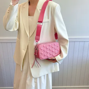 Pink quilted crossbody bag with fish scale pattern and wide strap on female model