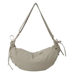 Minimalist beige dumpling crossbody bag with drawstring details and adjustable strap