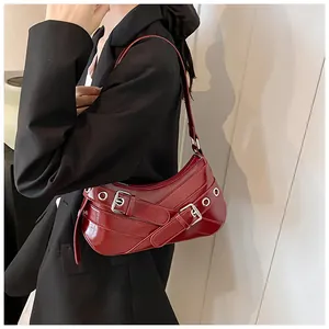 Detail of burgundy Y2K underarm bag with silver eyelets and buckle on model in black suit