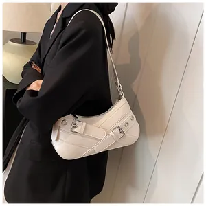 Detailed close-up of white leather shoulder bag featuring silver buckle and eyelet belt straps