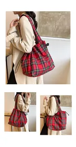 Detailed view of red tartan canvas bucket bag with drawstring closure and wide shoulder strap