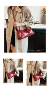 Détail du sac bandoulière vintage rouge foncé en cuir ciré avec œillets métalliques