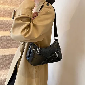 Modern black crescent underarm bag with silver grommets and buckles on a stylish shoulder strap