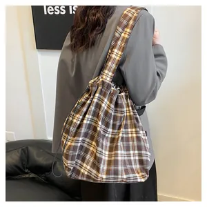 Rear view of model wearing a vintage brown checkered drawstring bucket bag with wide strap