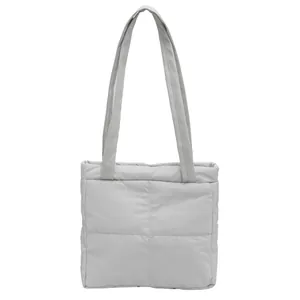 Detailed macro view of light gray quilted nylon fabric and stitching on the tote bag