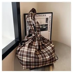 Detail view of coffee and cream plaid tote bag featuring drawstring closure and soft texture