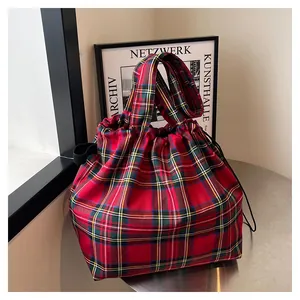 Detailed view of red plaid tote bag with black drawstring closure and durable handles