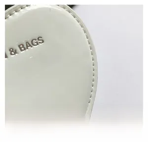 Macro shot of white glossy mirror leather with silver 3D metal letters and stitching