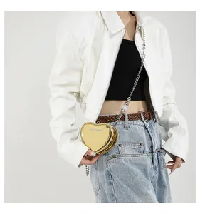 Model wearing a gold heart-shaped mini crossbody bag with a metallic mirror finish