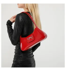 Borsa a spalla in pelle verniciata rossa con fiocco argento e finitura lucida su modella