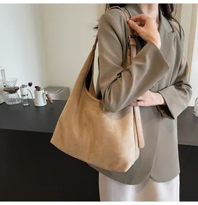 Macro view of a large camel suede hobo bag featuring adjustable leather shoulder straps