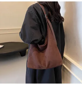 Detail of adjustable leather strap and silver buckle on dark brown suede hobo bag