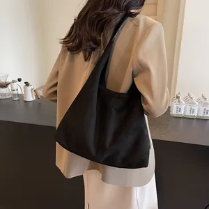 Large black faux suede tote bag for women worn over shoulder in a minimalist commute style